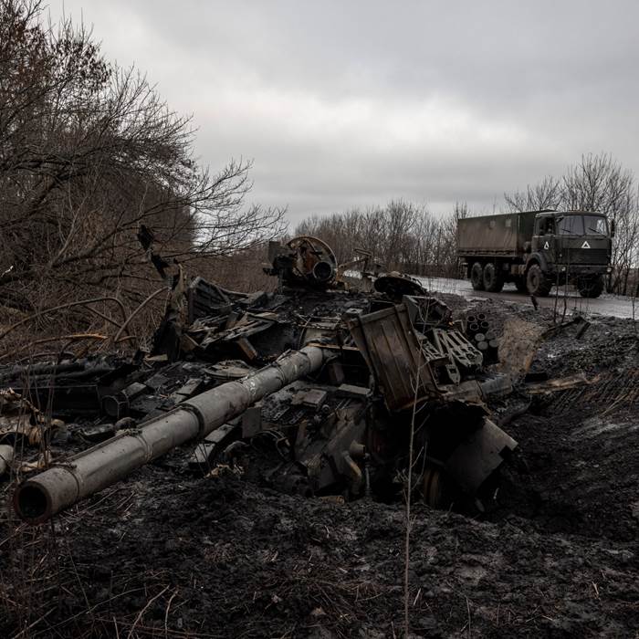 A wrecked tank on a blackened roadside.
