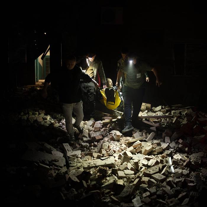 People with flashlights walking amid rubble.