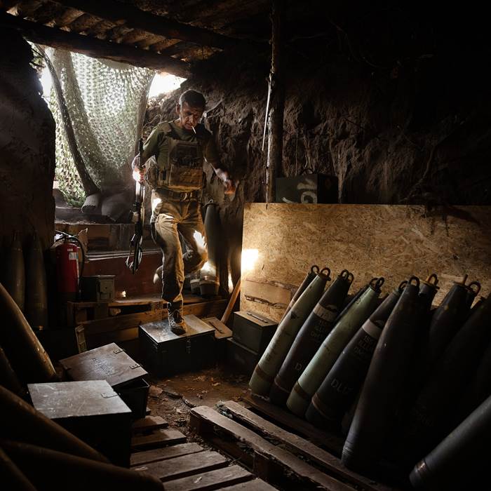 A man in fatigues walking among artillery shells.